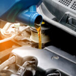 Kontrola hladiny motorového oleja pomocou mierky pri otvorenej kapote auta.