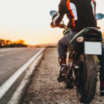Motocyklista v kompletnom ochrannom oblečení s prilbou a chráničmi tela.