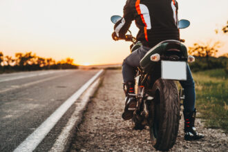 Motocyklista v kompletnom ochrannom oblečení s prilbou a chráničmi tela.