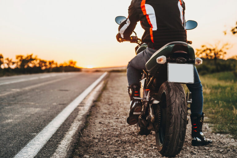 Motocyklista v kompletnom ochrannom oblečení s prilbou a chráničmi tela.