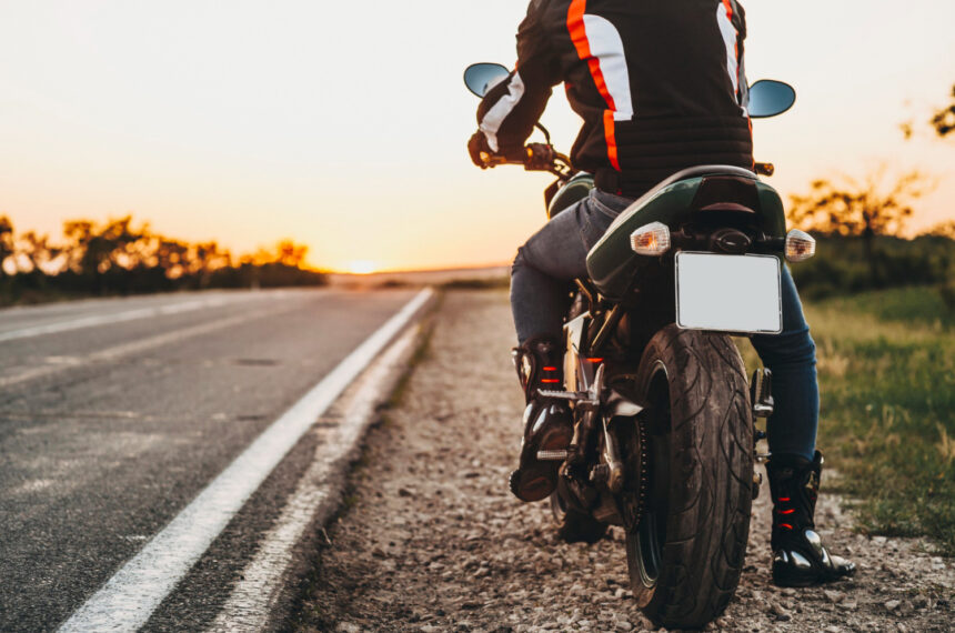 Motocyklista v kompletnom ochrannom oblečení s prilbou a chráničmi tela.